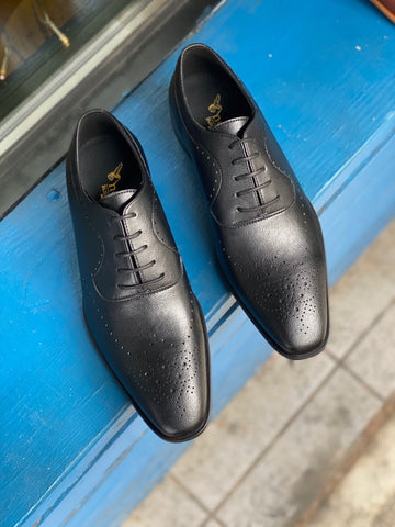 A pair of black vegan leather men's dress shoes with subtle perforated detailing. Lace up closure with 5 eyelets. Slightly tapered squared toe.